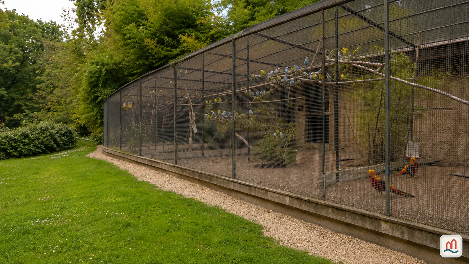 La grande serre du Jardin des Plantes de Rouen au bout de l'allée centrale, entourée de massifs fleuris.